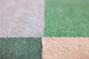 A green and white patterned carpet tile needing regular cleaning to maintain its appearance and lifespan.